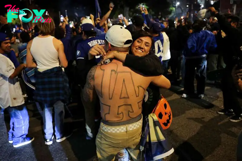 A person embraces a Dodgers fan showing his LA Dodgers logo tattooed on his body during celebrations on the street after the Los Angeles Dodgers' victory over the New York Yankees to win the World Series in Los Angeles.