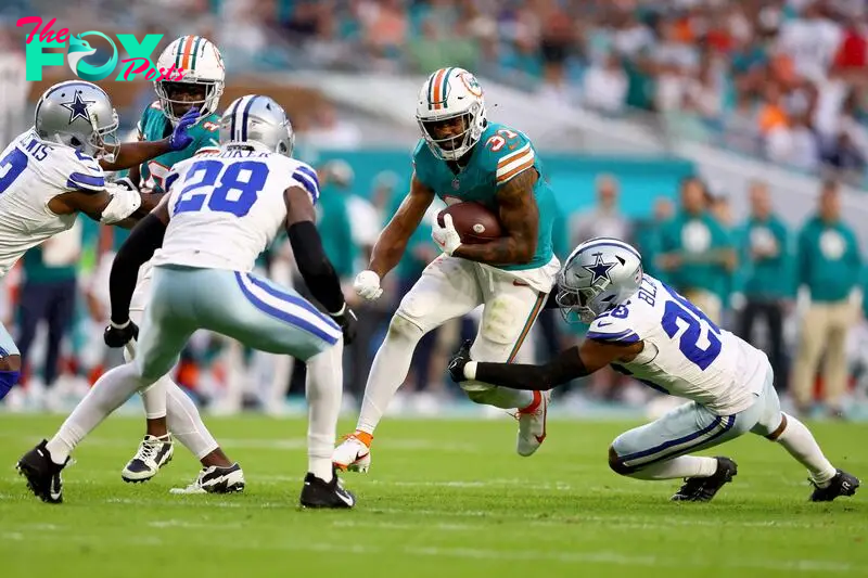 Raheem Mostert of the Dolphins is tackled by DaRon Bland.