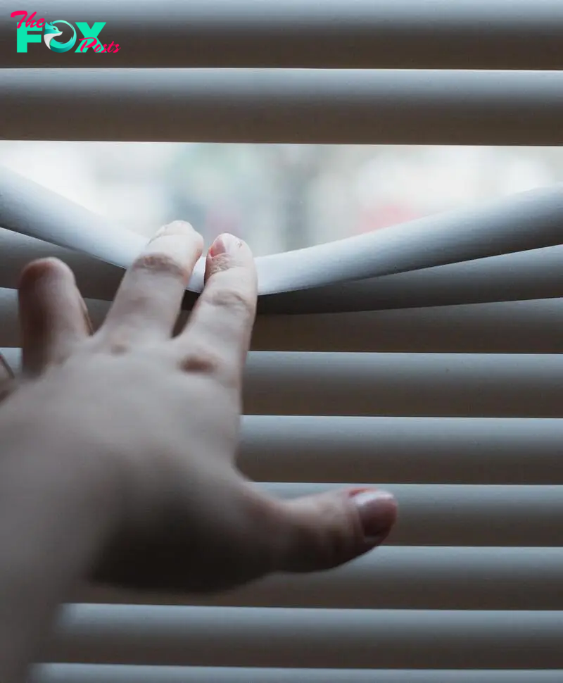 A person's hand on window blinds | Source: Pexels