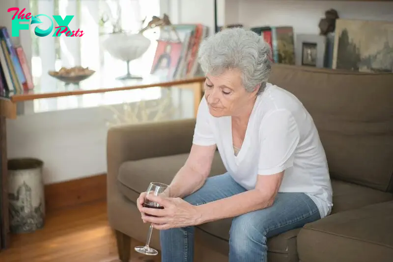 A sad-looking woman drinking a beverage while seated on a couch | Source: Pexels