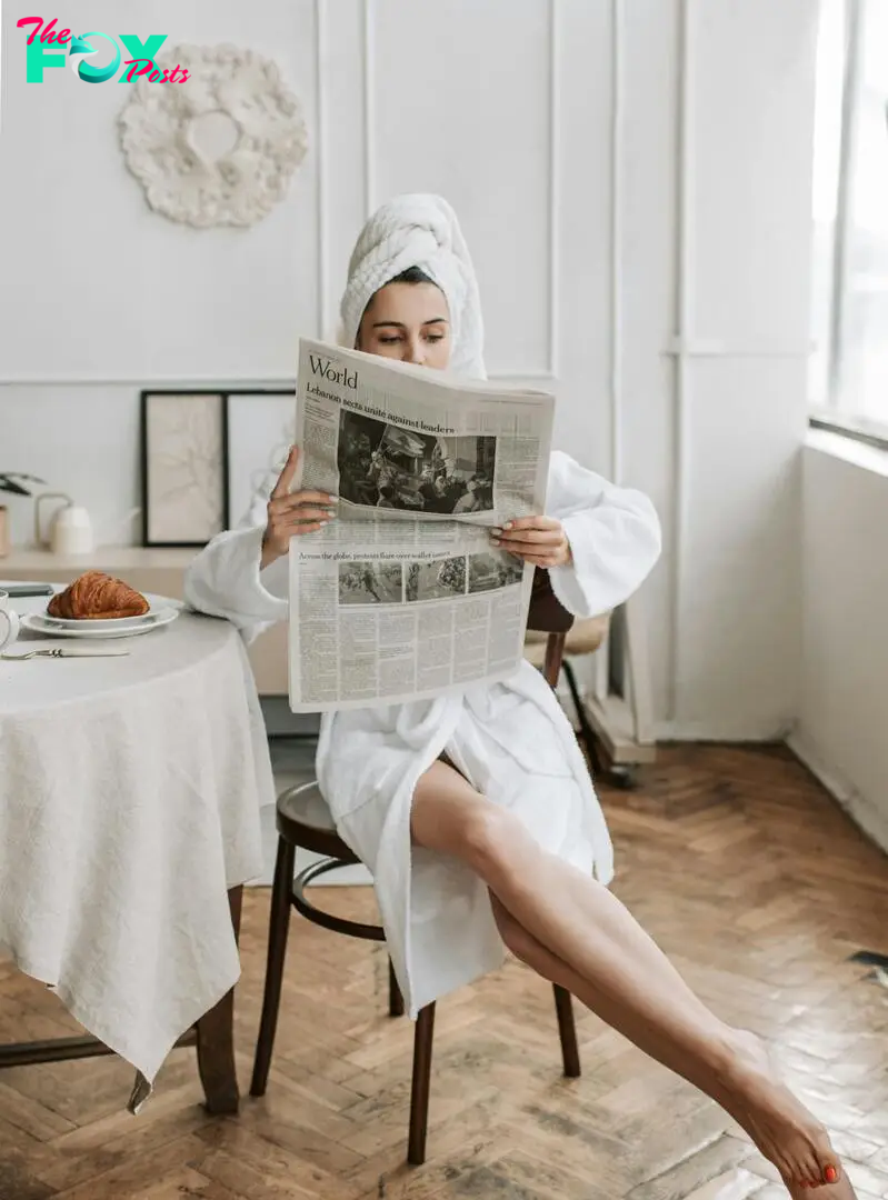 A woman reading a newspaper after showering | Source: Pexels