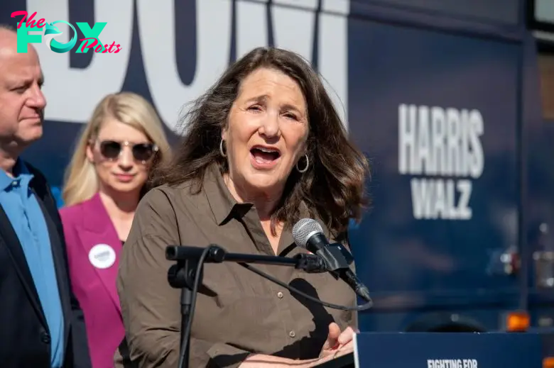 Diana DeGette speaks passionately at a podium during an abortion rights rally, with two people standing behind her.