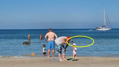Terrifying detail in background of innocent family beach photo sparks debate