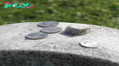 Why do some people place coins on gravestones?