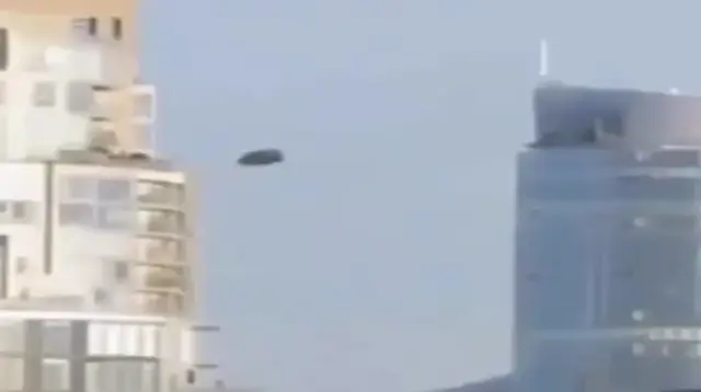 A UFO with a silvery metallic sheen can be seen flying over the center of Mexico City during the day (Video)